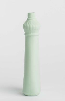 Prikazana je vaza brenda foekje fleur u svijetlo zelenoj boji ispred sive pozadine. Vaza je prikazana s bočne strane, ima oblik kontejnera za sredstvo za pranje suđa.