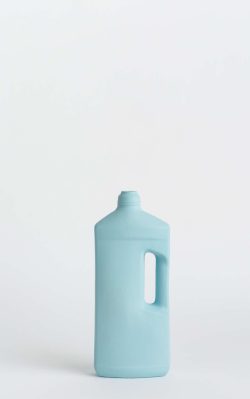 Prikazana je vaza brenda foekje fleur u svijetlo plavoj boji ispred sive pozadine. Vaza ima oblik kontejnera za sredstvo za pranje suđa.