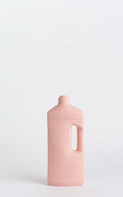 Prikazana je vaza brenda foekje fleur u svijetlo ružićastoj boji ispred sive pozadine. Vaza ima oblik kontejnera za sredstvo za pranje suđa.