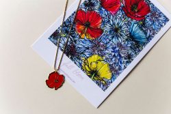 Pozlaćeni lančić s privjeskom u obliku cvijeta maka, emajliranim crvenom bojom uz ilustraciju maka na podlozi