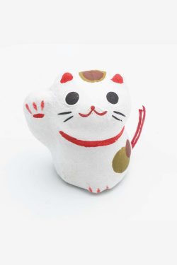 Na slici se vidi mala figurica mačkice od papirmašea u biljeloj boji. Mačkica drži desnu šapu u vis, u znak sreće. Ima crvenu ogrlicu i smješak na licu.