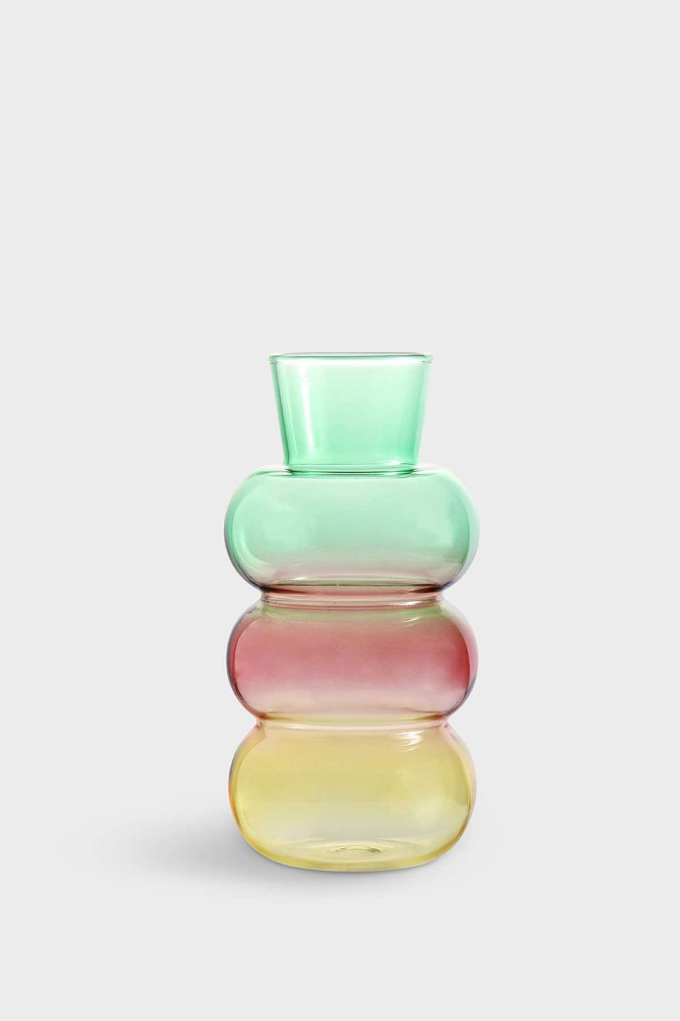 Na slici je prikazana staklena vaza u bojama koje se prelijevaju od žute na dnu preko crvene u sredini do zelene na vrhu. Vaza je trbušasta na dnu, ima dva zadebljanja u sredini, a na vrhu se otvara konusno.