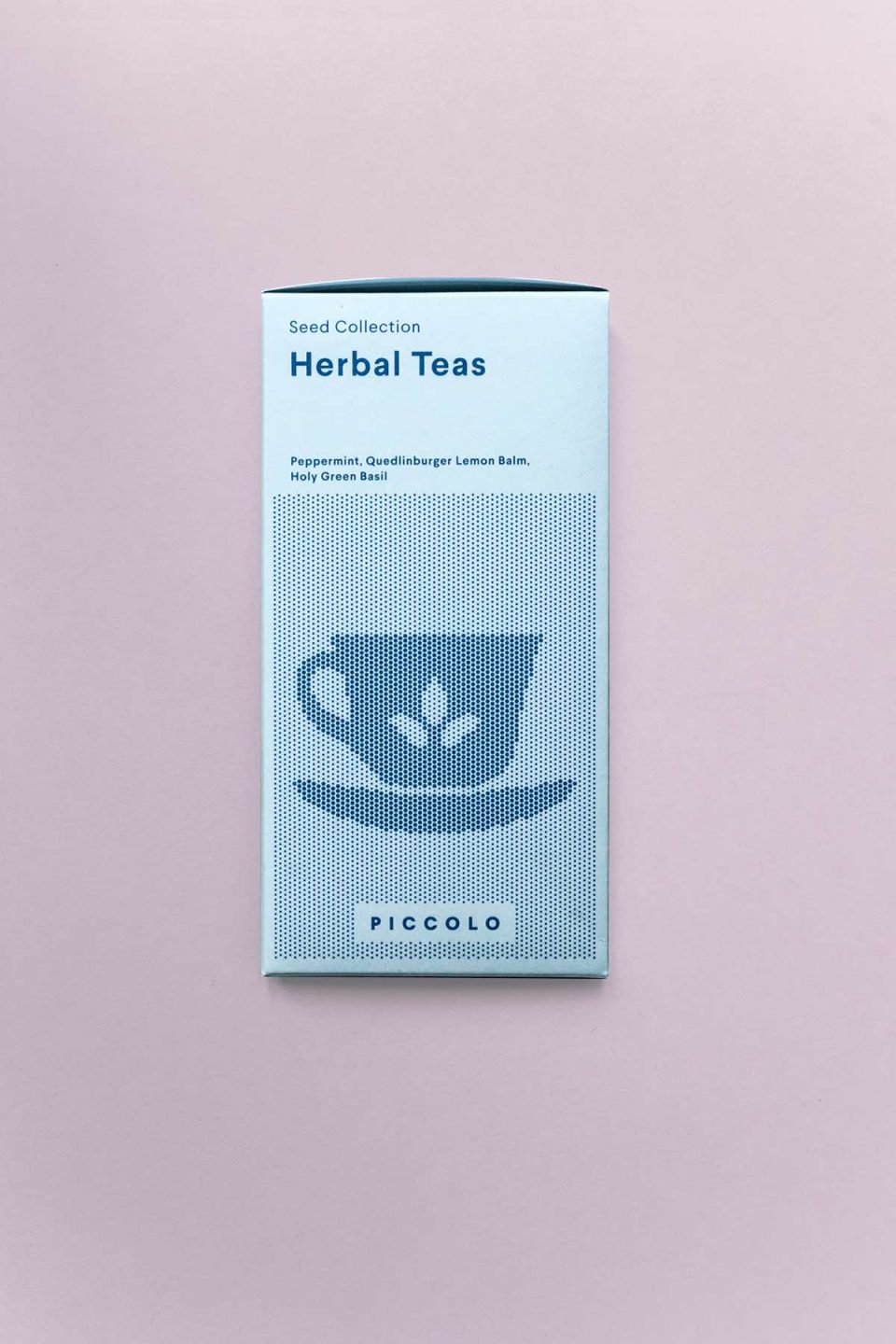 Plava kutija sjemenki s biljem od kojeg se ogu napraviti čajevi na rozoj podlozi